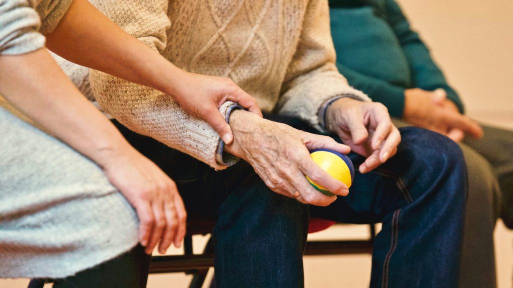 Ältere Person hält ein Ball, Ältere Person ist pflegebedürftig, Rentner in einem Pflegeheim, Pflegeheimkosten, Pflegekosten