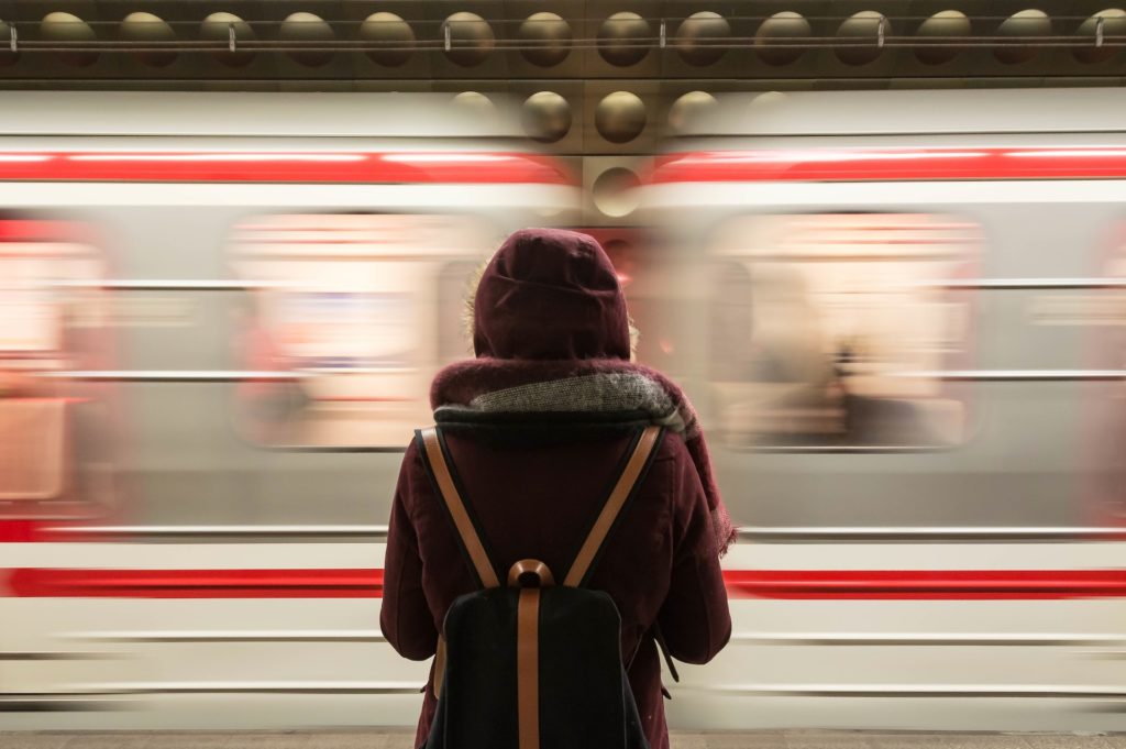 Frau steht am Bahnhof vor einem fahrenden Zug, Mobilitätsprämie: Was solltest du wissen?